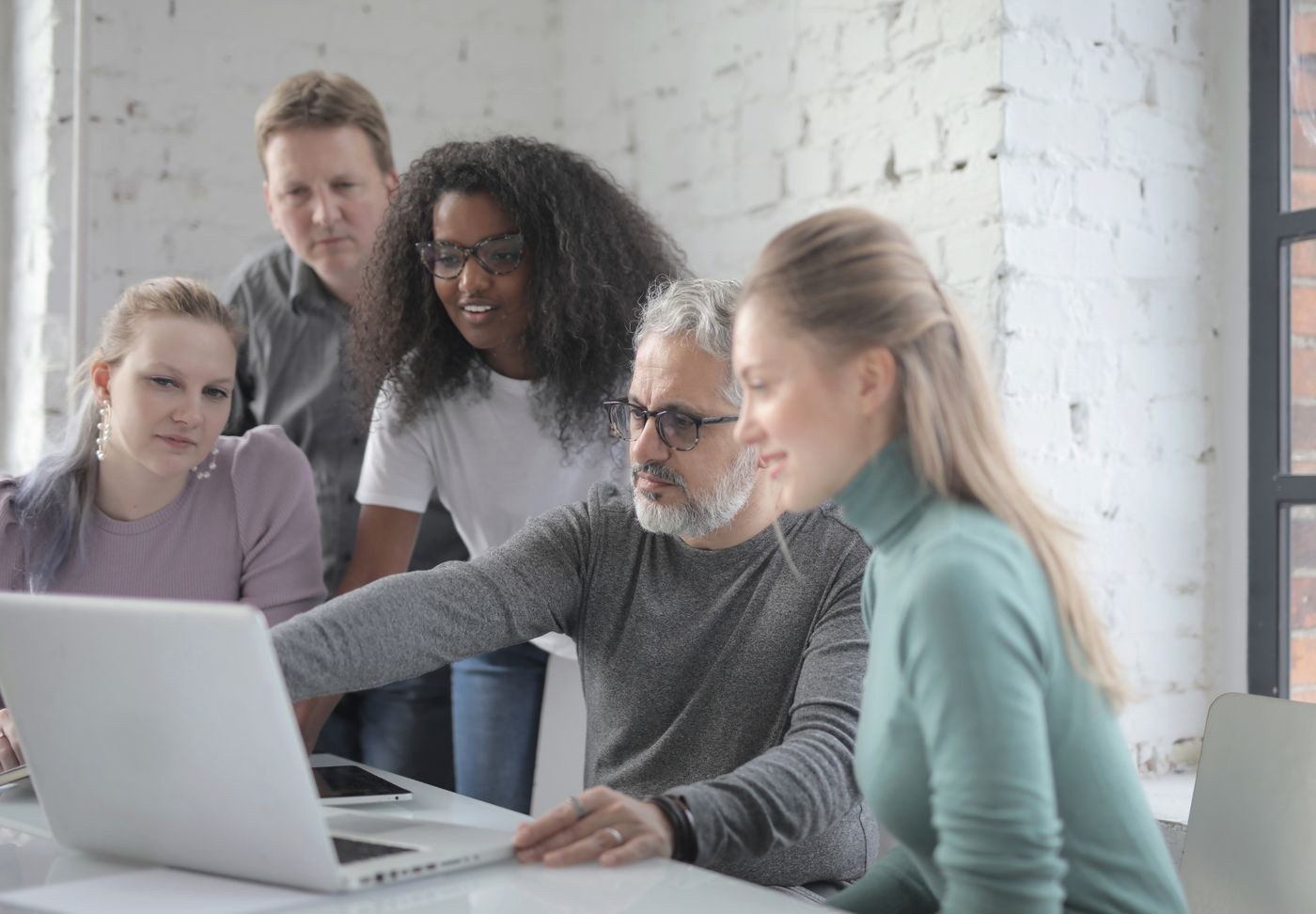 Profissionais colaborando ao redor de um notebook em um escritório